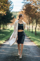 Woman wearing Silk Closet black cropped silk cami and matching silk skirt. Cream jacket