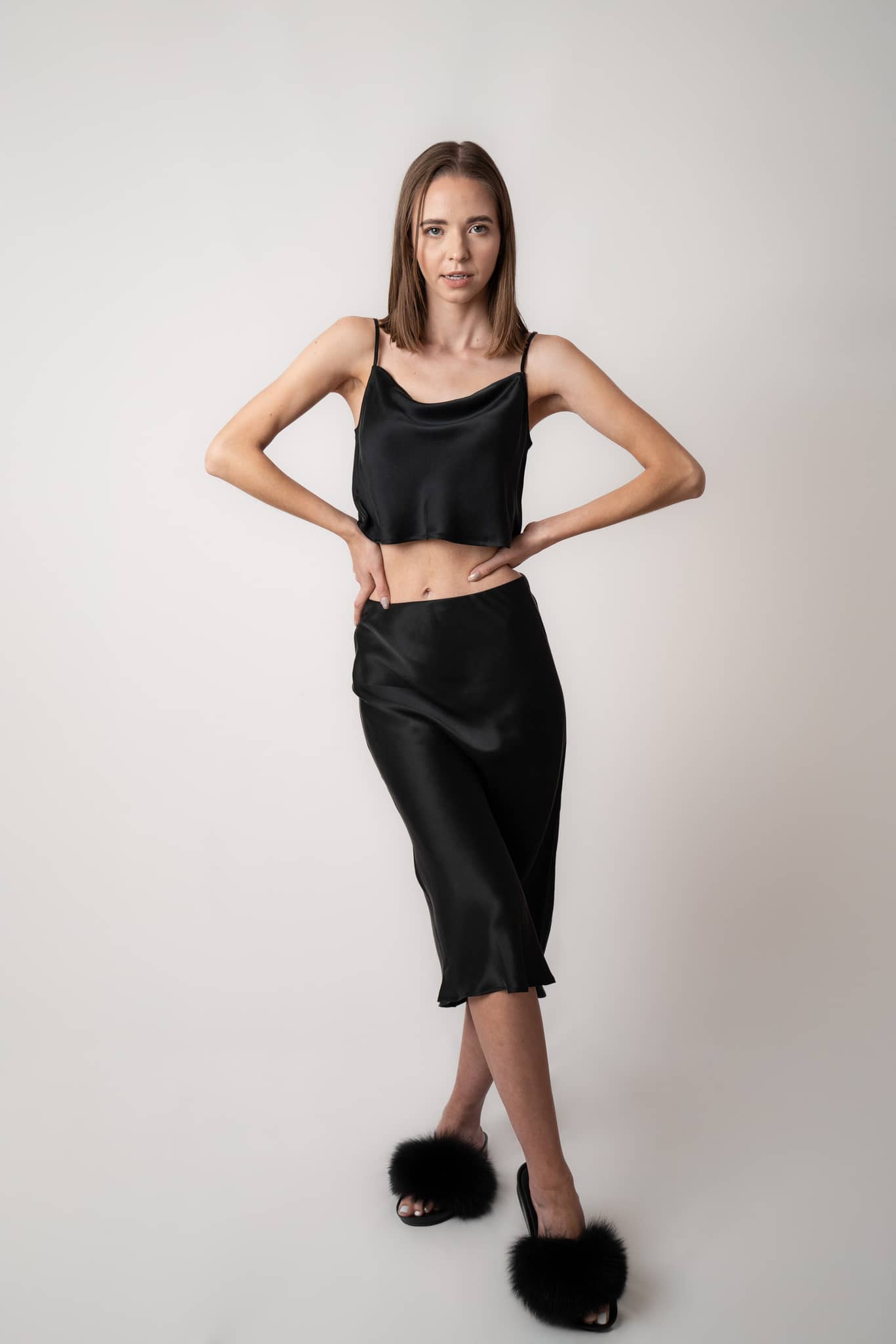 Woman wearing Silk Closet black cropped silk cami and matching silk skirt in studio.