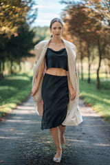 Woman wearing Silk Closet black cropped silk cami and matching silk skirt. Wearing jacket.