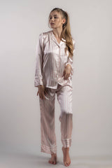 Woman wearing silk closet pink and white striped long pyjama set pants in studio.